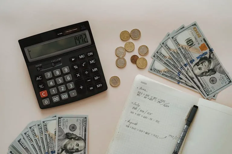 Flat lay of calculator, cash, coins, and handwritten notes for budget planning.
